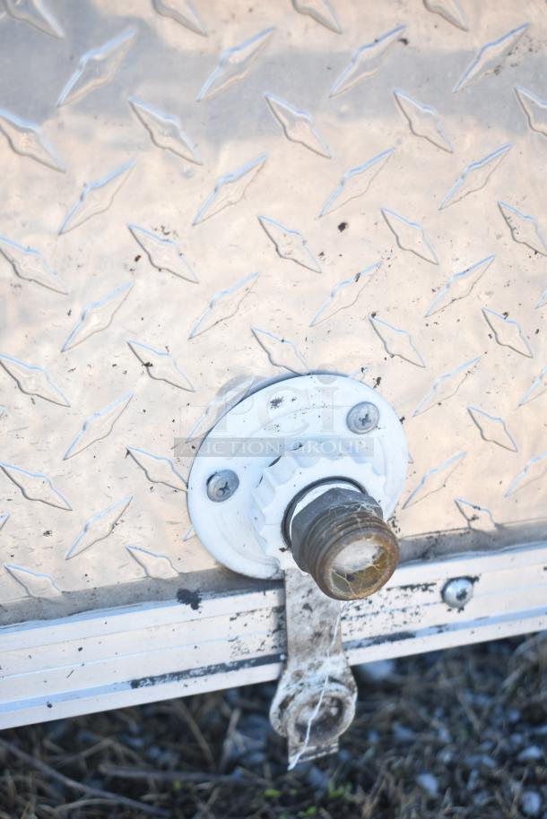 Close-up of a 2021 Diamond Cargo 8.5' x 24' trailer's metal exterior with textured diamond plate and trailer hitch.