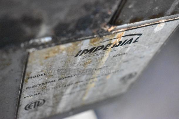 Label on electrical component, marked “IMPERIAL,” showing model and electrical supply details, aged with rust.