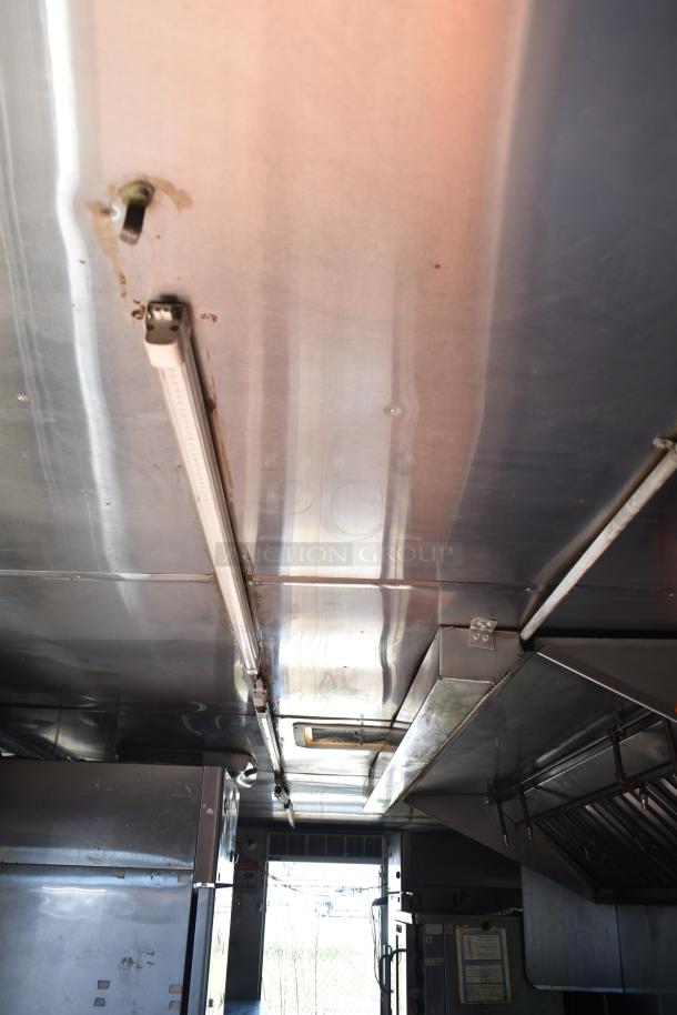 Interior view of 2012 Quality Cargo food trailer showing stainless steel ceiling, lighting, and ventilation hood.