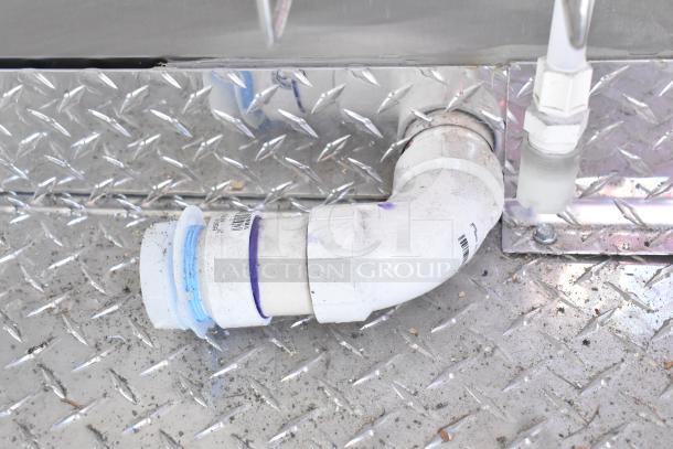 Close-up of Diamond Cargo food trailer underside with visible piping and diamond plate metal finish, showing utility connections.