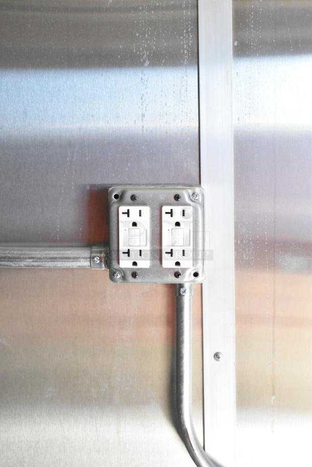 Electrical outlet inside 2021 Diamond Cargo 8.5' x 24' food trailer. Shown with metal conduit and stainless steel wall.
