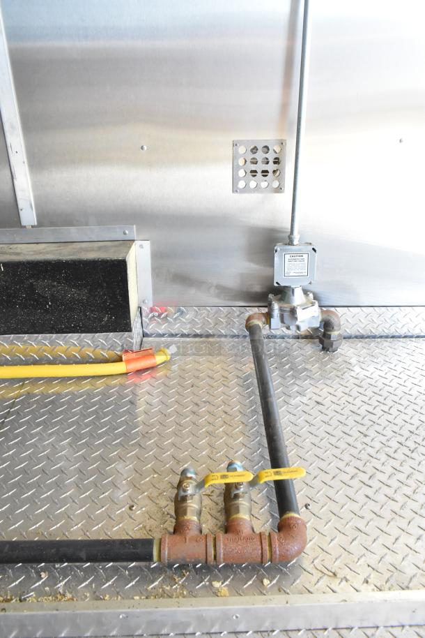 2021 Diamond Cargo 8.5' x 24' food trailer interior with grease hood and plumbing system. Heavy-duty diamond plate flooring.