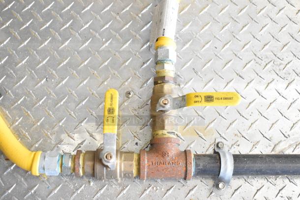 Gas valves on a diamond plate floor, showing yellow levers marked "SMP Valve" and rust on connected pipes.