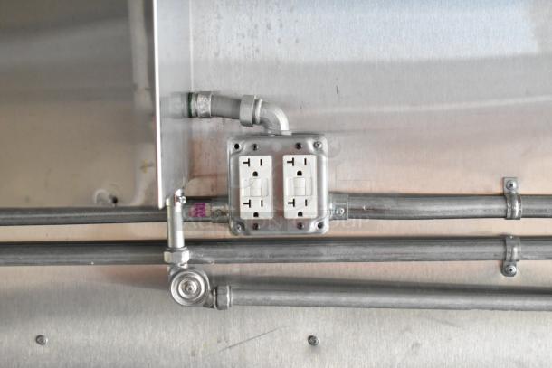 Electrical outlet with metal conduit inside a 2021 Diamond Cargo food trailer. Stainless steel wall shown.
