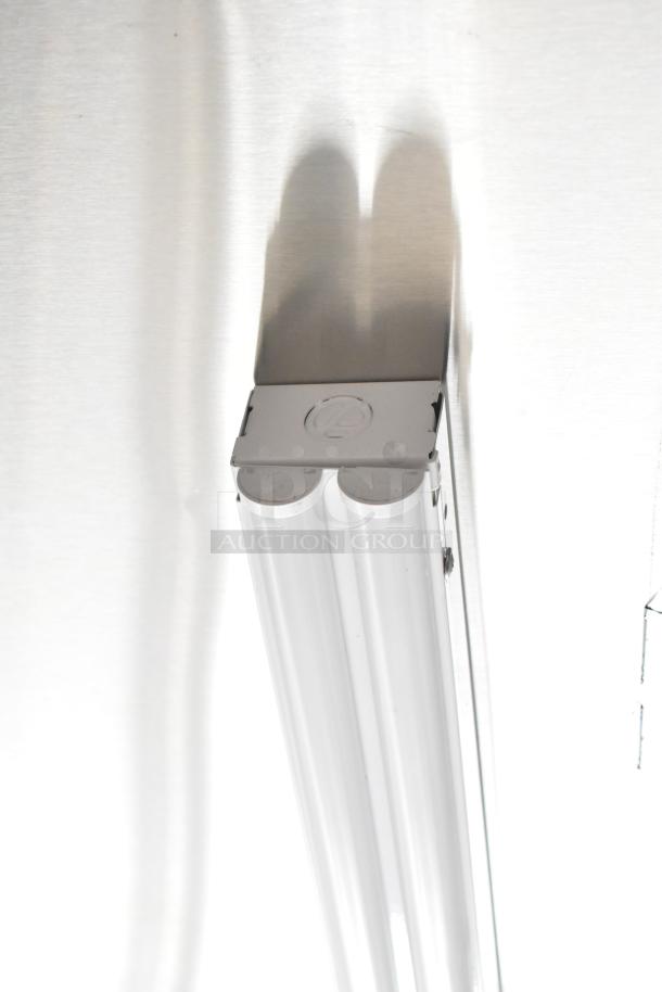 Fluorescent light fixture attached to a metallic surface, showing a dual-tube design.