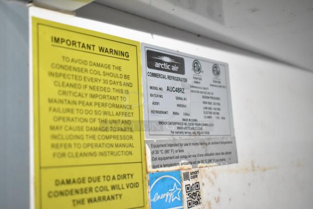 Warning and specifications labels on Arctic Air commercial refrigerator, model AUC48RZ, featuring maintenance instructions.