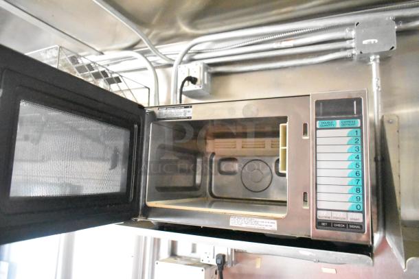Interior of a Diamond Cargo mobile kitchen, showing a microwave with a numeric keypad and ventilation system.