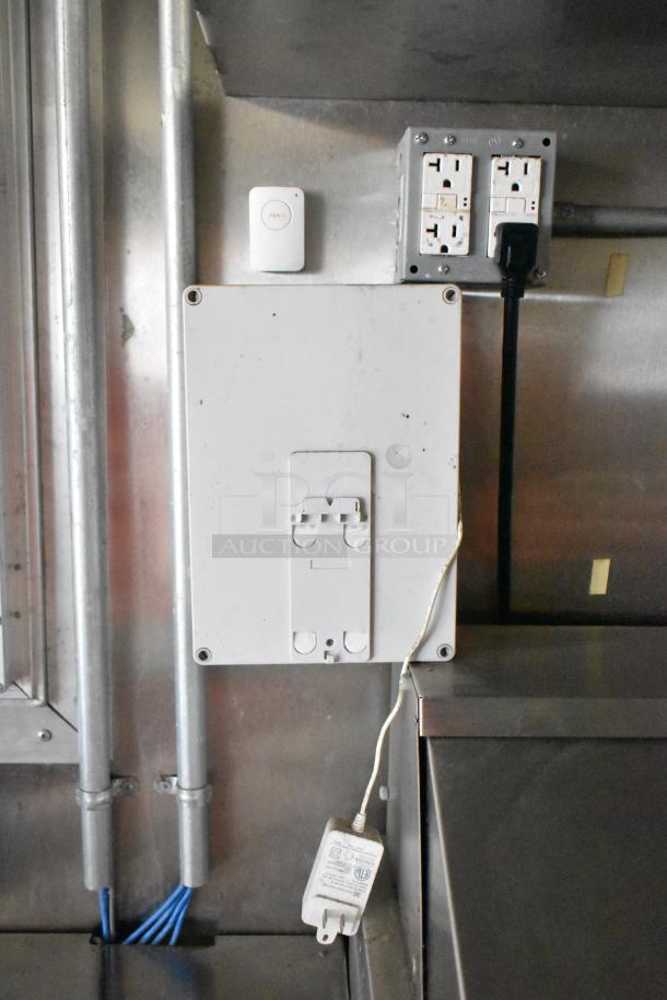 Panel with a panic button and dual electrical outlets inside a 2020 Diamond Cargo mobile kitchen trailer.