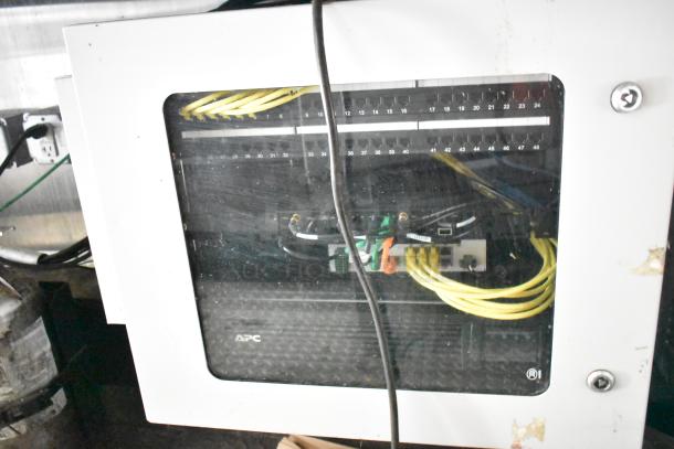APC network panel in Diamond Cargo kitchen trailer, showing organized cables and a secured enclosure, part of mobile kitchen setup.