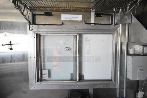 Interior view of 2020 Diamond Cargo mobile kitchen trailer. Features include metal shelving, service window, and electrical outlets.