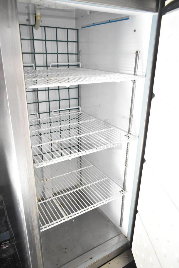 Inside view of the refrigeration unit in the 2020 Diamond Cargo mobile kitchen trailer, showing three metal shelves.