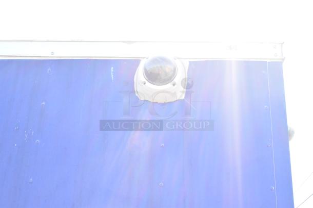 Exterior of Diamond Cargo mobile kitchen trailer, featuring a blue panel and mounted security camera under sunlight.