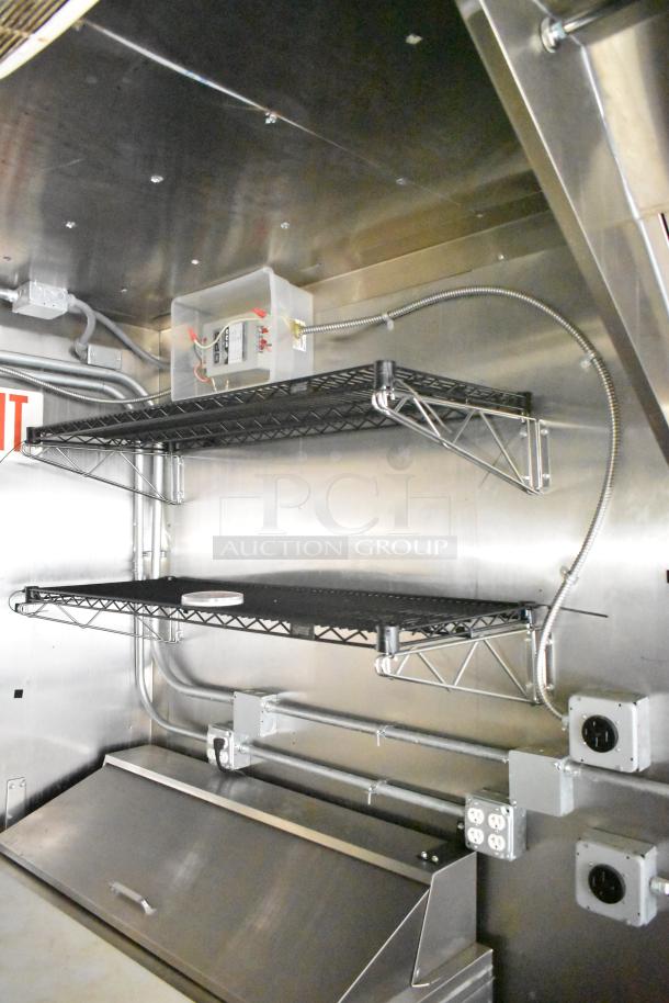 Interior of 2021 Diamond Cargo 8.5' x 24' cold food trailer, showing metal shelves, outlets, and sleek stainless steel finish.