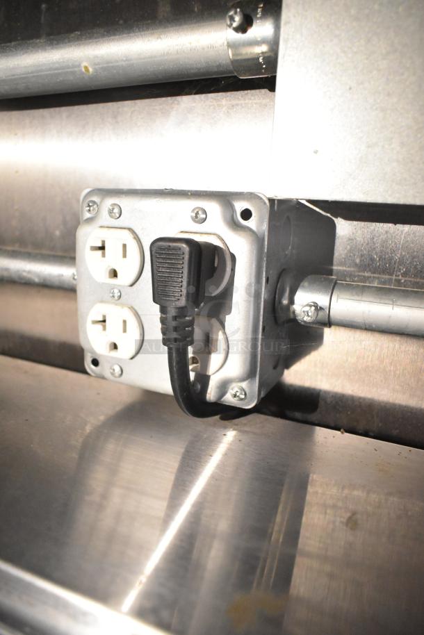 Electrical outlet in Diamond Cargo cold food trailer, showing a power plug connected. Stainless steel surface visible.