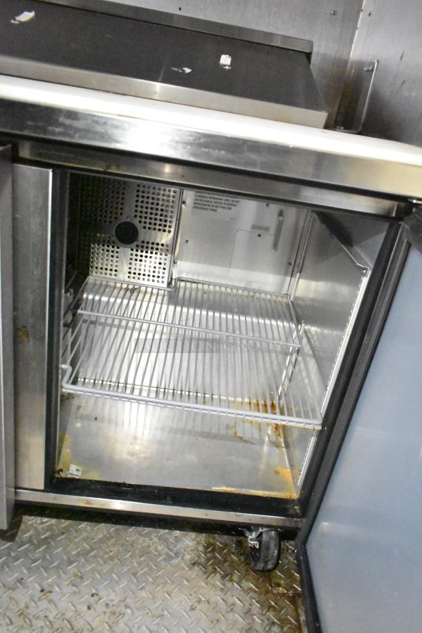 2021 Diamond Cargo 8.5' x 24' cold food trailer interior, showing a used metal storage compartment with wire shelves.