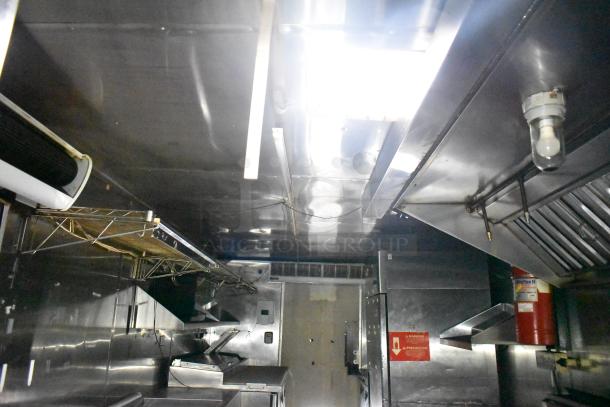 Interior of 2019 Quality Cargo 24ft food trailer with grease hood, Royal Range Griddle, gas fryer, and refrigeration units.