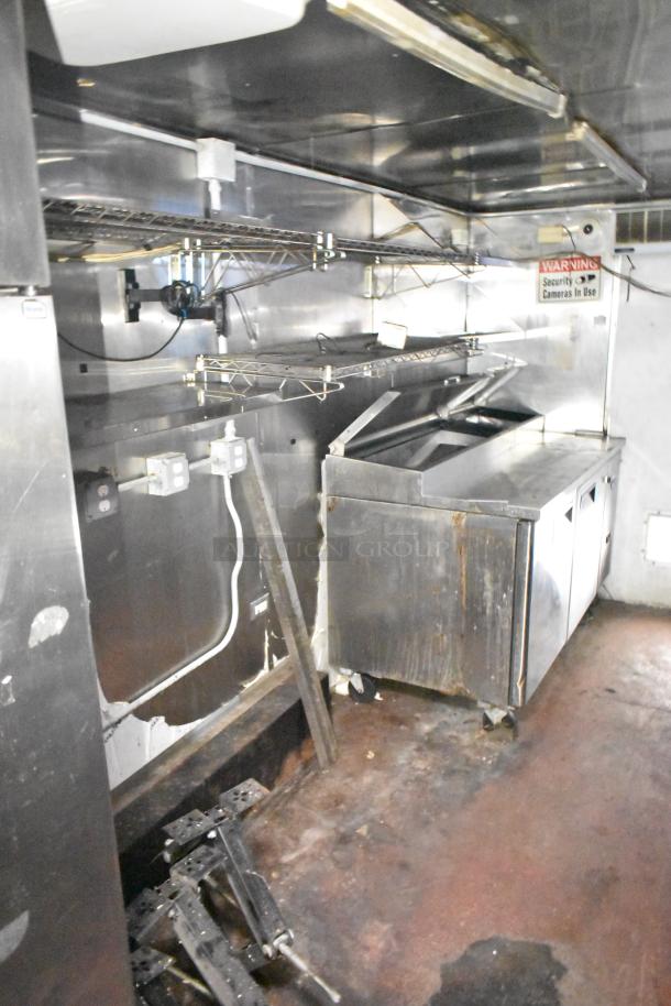 2019 Quality Cargo 24' food trailer interior, showing stainless steel countertops, grease hood, and fryer. Signs of wear visible.