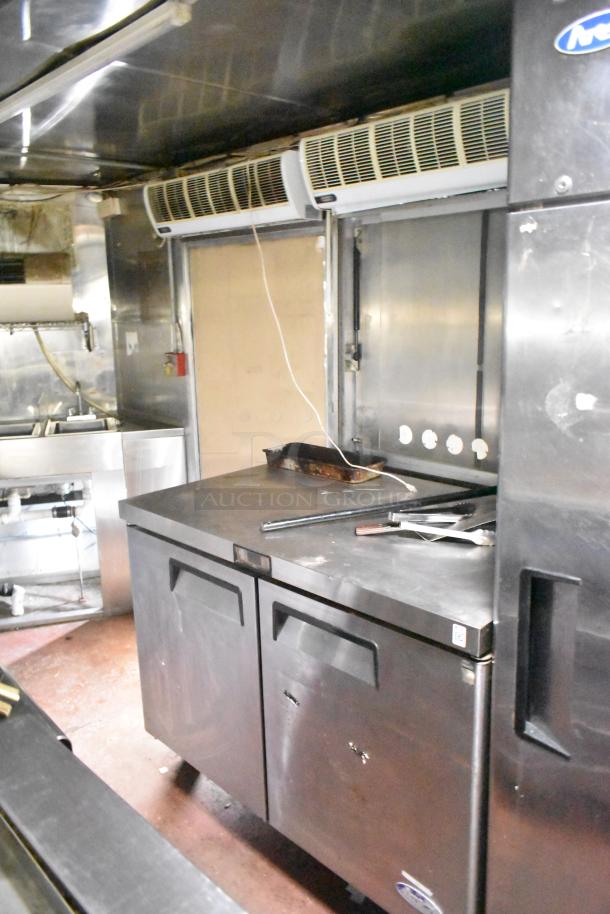 2019 Quality Cargo 24' food trailer interior with stainless steel counters, grease hood, fryers, and grill. Outfitted for commercial use.