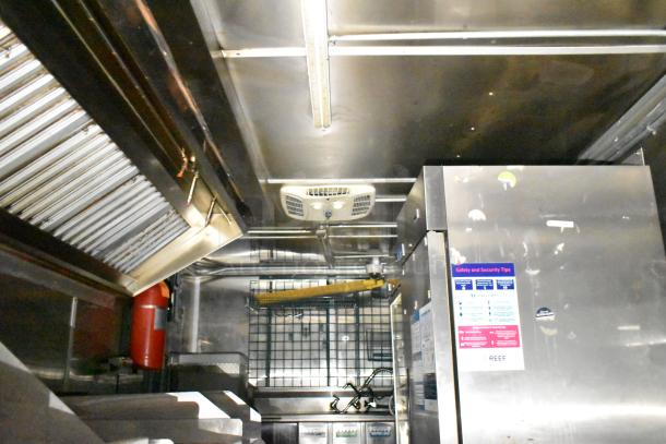 2020 Diamond Cargo 24' commercial kitchen trailer interior showing grease hood, refrigeration unit, and safety signage.