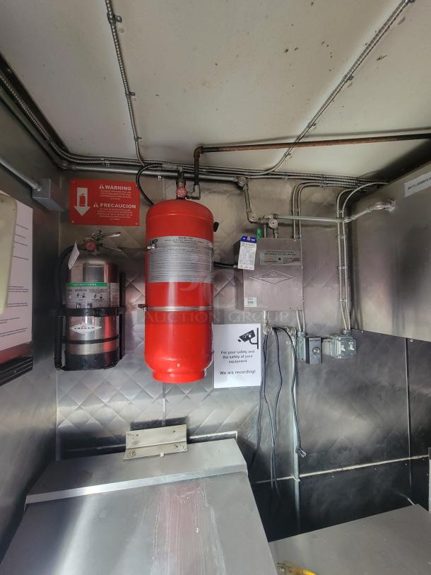 2018 Quality Cargo 16' food trailer interior with fire extinguisher system, stainless steel walls, and visible safety signage.