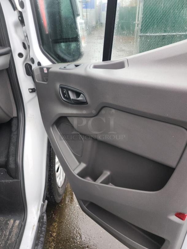 Interior view of a 2020 Ford Transit 350 Cargo Van door panel, showcasing power window controls and storage compartments.