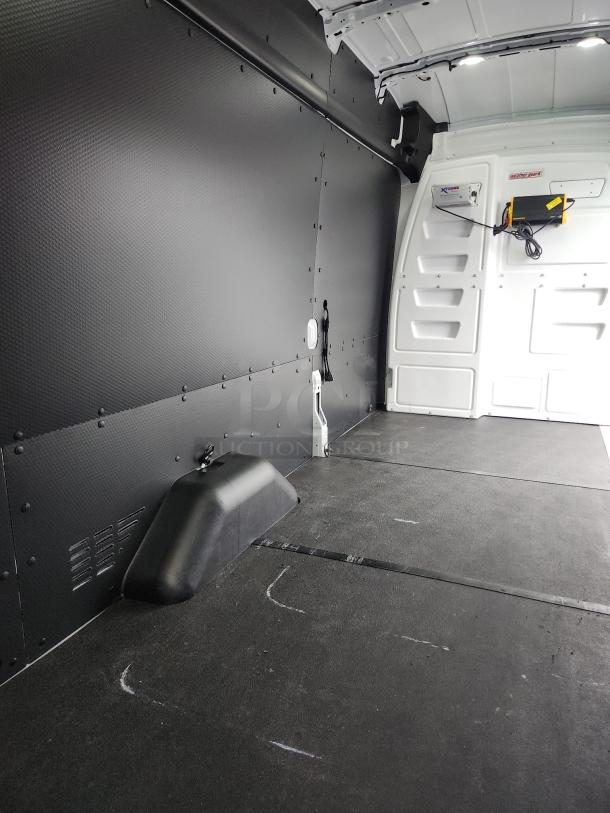 Interior of 2020 Ford Transit 350 Cargo Van. High Roof with clean cargo area, partition, and protective liners. Minimal wear.