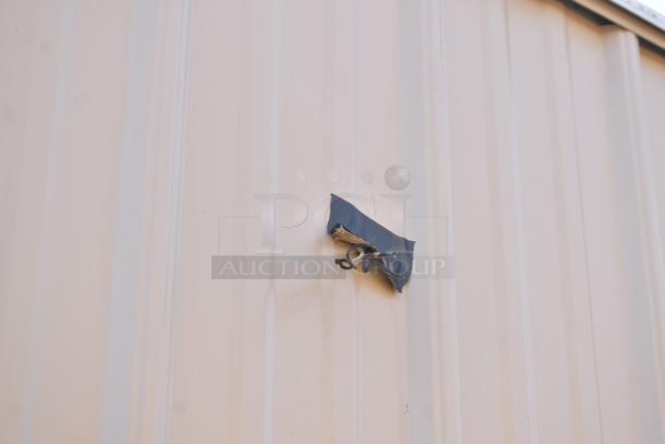 Exterior close-up of unbranded food trailer, showing taped cable and connection on metal siding.