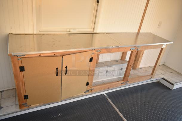 Unbranded food trailer interior with metal counter, wooden cabinets, Diehard battery, Eaton power box, ventilation fan, used condition.