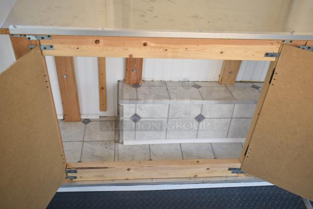 Unbranded food trailer interior with open wooden cabinet, tiled floor, and visible vent. Includes Diehard 27DC-2 Battery.