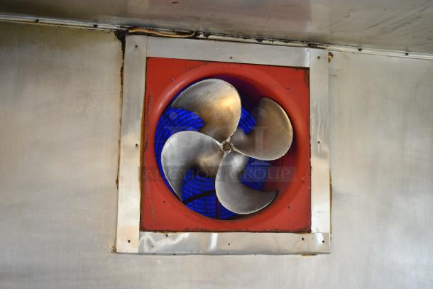 Ventilation fan inside food trailer, featuring a red frame and a metallic fan blade.