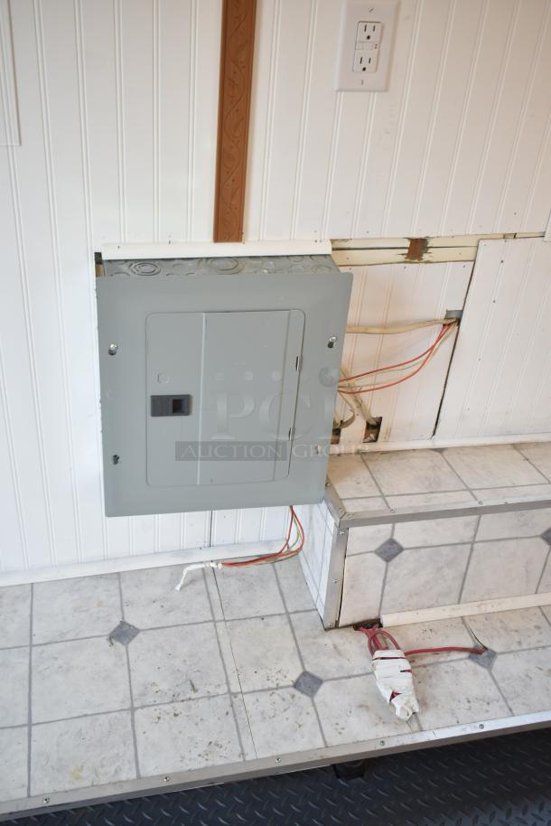 Inside view of unbranded food trailer showing Eaton power box, cables on tiled floor, and white paneled wall.