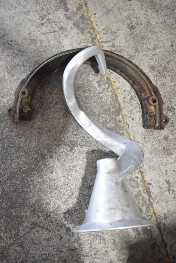 Hobart L800 dough hook attachment on concrete floor, showing metal finish and sturdy design.