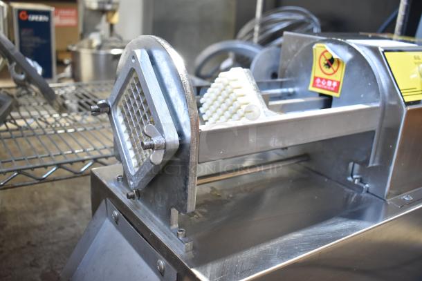 Stainless steel electric vegetable cutter on casters with a grid blade, showing clean and robust design in commercial setting.