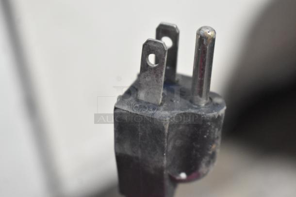 A close-up of an electrical plug, showcasing a three-prong design, for a stainless steel electric vegetable cutting machine.