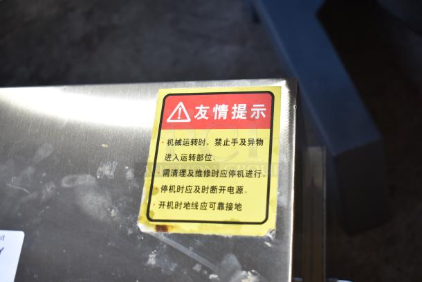 Stainless steel commercial vegetable cutter with safety warning label in Chinese. Electric, on casters, suitable for multifunctional use.