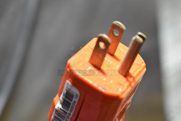 Close-up of an orange plug with three prongs and a visible barcode label.