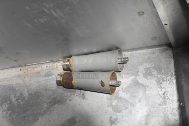 Two metal support legs with some rust, likely from the Traulsen G31010 commercial freezer, showing signs of wear.