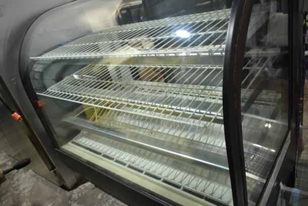 True TCGR-50 refrigerated display case, commercial floor style, 115 volts, 1 phase. Features curved glass, multiple shelves, signs of wear.