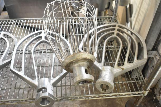 Three Hobart mixer attachments: 60-quart whisk, 60-quart paddle, 80-quart paddle. Visible wear, metal construction.