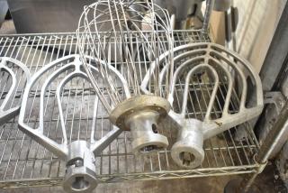 Three Hobart mixer attachments: 60-quart whisk, 60-quart paddle, 80-quart paddle. Visible wear, metal construction.