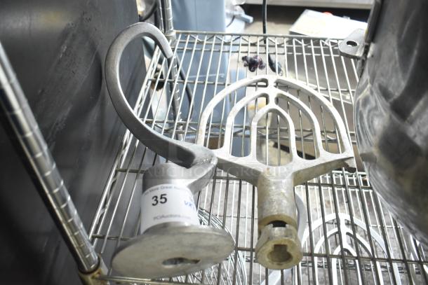 Two Hobart mixer attachments: dough hook and 30-quart paddle, silver tone, used condition, on wire rack with auction label.
