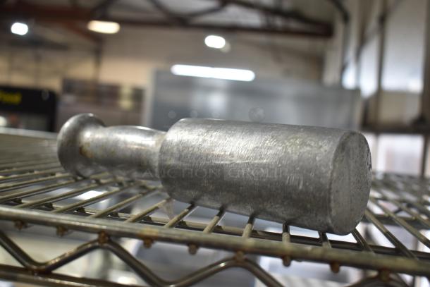 Metal kitchen tool on a wire shelf, possibly part of a Hobart mixer accessory set for auction.