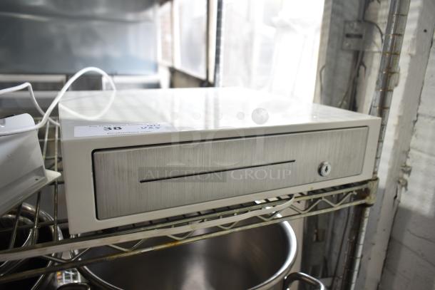 Clover D100 cash drawer in stainless steel, with visible key lock, on a metal shelf. Auction tag on top.