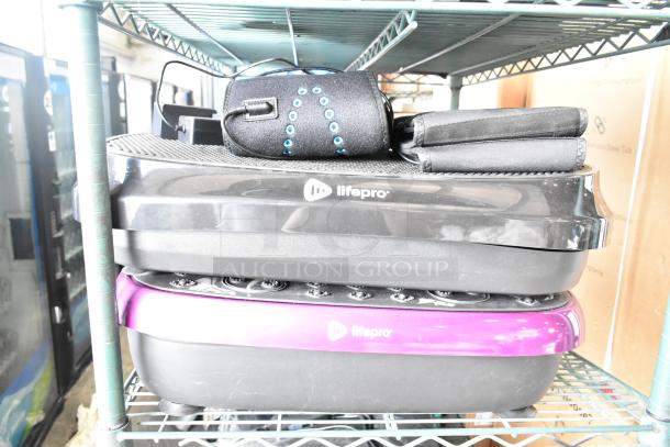 Four items including two LifePro vibrating plates, black and purple, with control panels. Good condition.