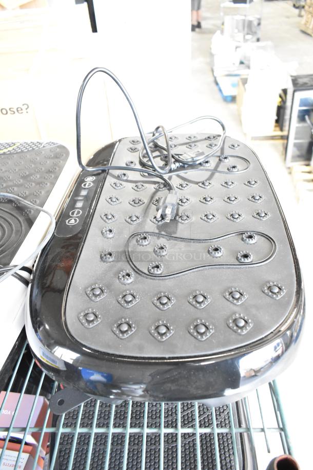 A Hurtle HURVBTR36 vibration plate, black with textured surface, power cord shown, laid on a warehouse shelf.