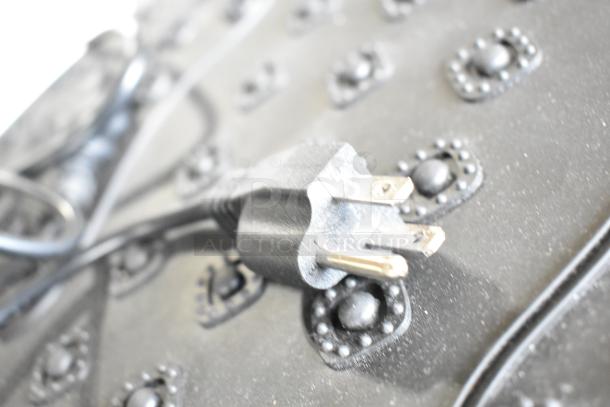 Close-up of a power cord on a black surface with textured patterns, likely from one of the electronic auction items.
