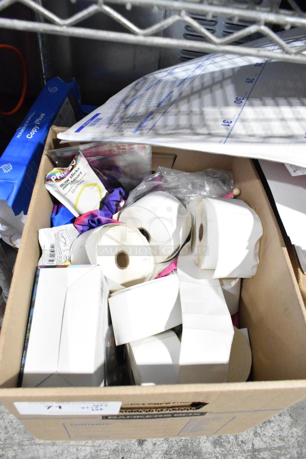 Cardboard box containing Pride string lights, light-up bracelets, exam table paper, and Manila end tab file folders.