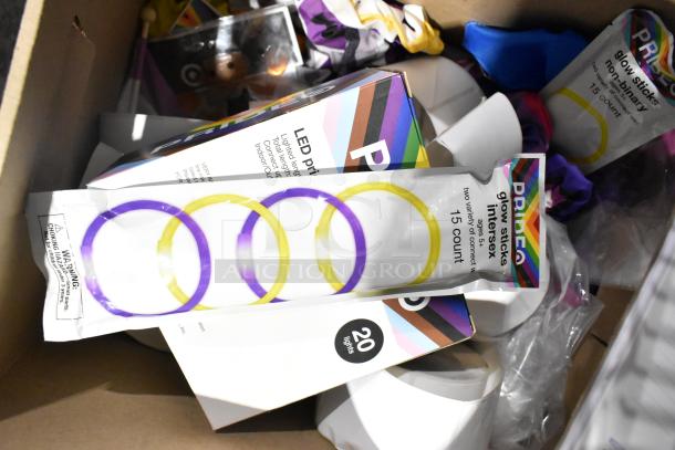 Mixed item lot including Pride string lights, light-up bracelets, exam table paper, and file folders. Variety of colorful packaging.