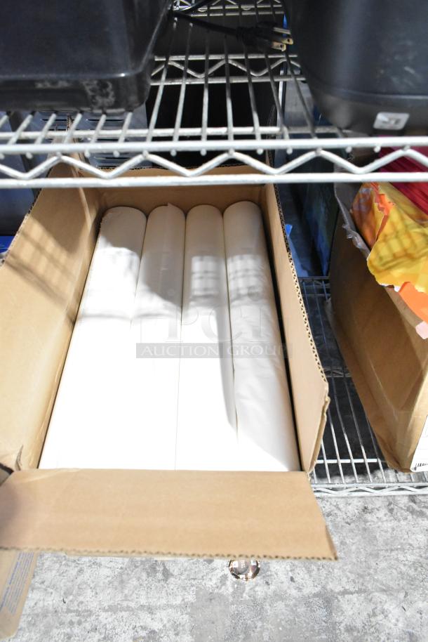 Cardboard box with exam table paper rolls on a metal shelf, part of a mixed auction lot.