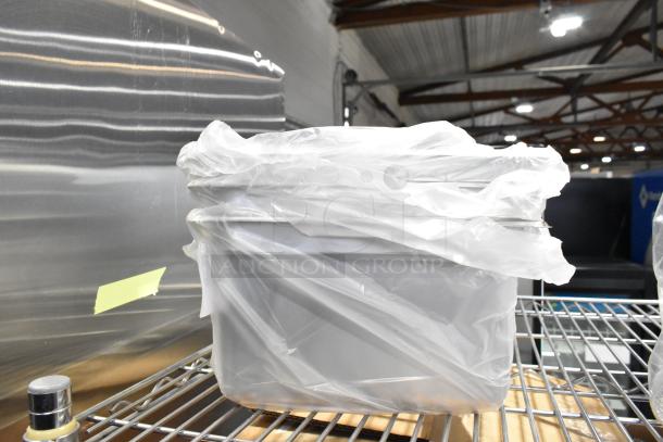 Brand new kitchen items wrapped in plastic, including bowls, food containers, and trays, on a metal shelf.